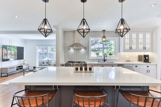 A modern and stylish kitchen with sleek white cabinetry, granite countertops, stainless steel appliances, and pendant lighting