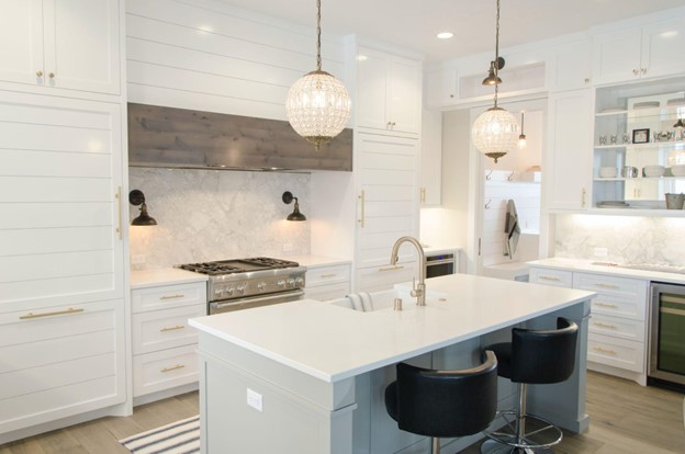 A modern and stylish kitchen with sleek white cabinetry, granite countertops, stainless steel appliances, and pendant lighting